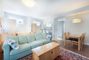 Ein modernes Wohnzimmer mit einem hellblauen Sofa, einem Holztisch und einem Essbereich mit einem Holztisch und Stühlen.