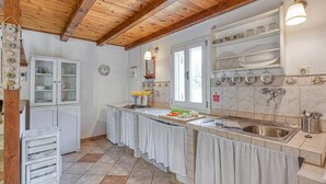 A kitchen with wooden beams, white cabinets, a sink, and a window.