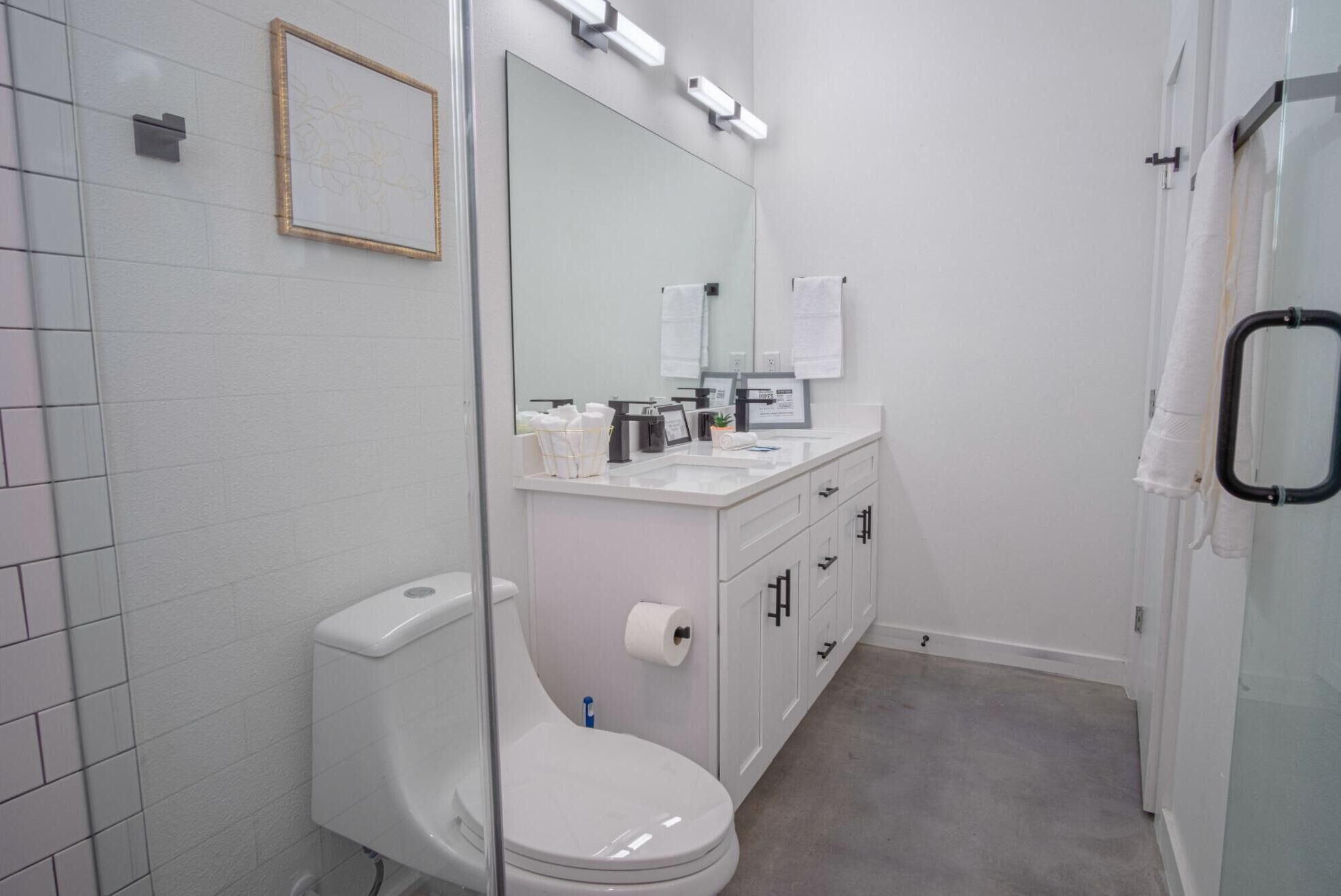 Un baño moderno con inodoro, lavamanos y espejo.