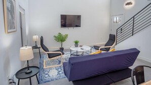 A modern living room with a flat-screen TV, two armchairs, a sofa, a small round table, and a potted plant. - Gorgeous 3 BR 2 BA Near Amazing Downtown (San Antonio)