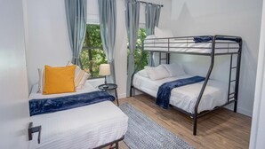 A bedroom with two bunk beds, a bedside table with a lamp, and a window with curtains. - Gorgeous 3 BR 2 BA Near Amazing Downtown (San Antonio)