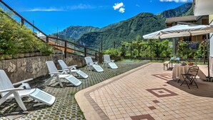 Een terras met lounge stoelen, een tafel met tafelkleed en uitzicht op een berg.