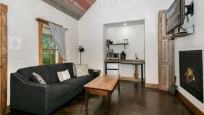 Un salon avec un canapé noir, une table basse en bois et une cheminée.