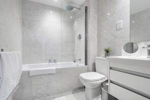 A modern bathroom with a glass-enclosed shower, a white toilet, and a vanity with a mirror. - The Cadogan Suite Next to Sloane Square (London)