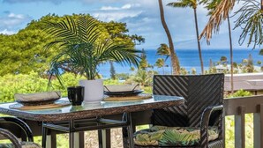 Een tafel buiten, met uitzicht op de oceaan en palmbomen.