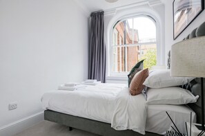 Ein Schlafzimmer mit Bett, Fenster und Lampe.