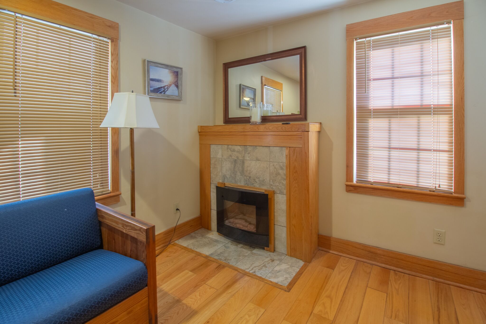 A room with a fireplace, a blue sofa, and a lamp.
