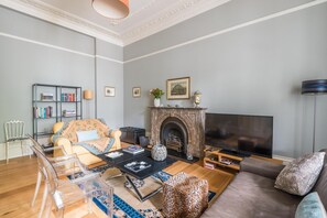 Ein Wohnzimmer mit Kamin, Sofa, Couchtisch und Fernseher.