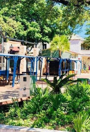 Un patio con una pérgola azul, un letrero con el número 325 y abundante vegetación verde.