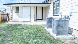 A single-story house with a front door, two windows, and two large air conditioning units on the right side. - Fascinating 1BR 1 BA Near Festive DT and Riverwalk (San Antonio)