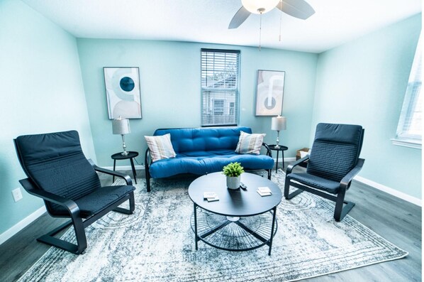 A modern living room with a blue sofa, two black chairs, a coffee table, and a ceiling fan. - Fascinating 1BR 1 BA Near Festive DT and Riverwalk (San Antonio)