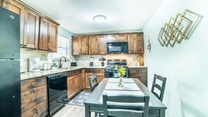 A compact kitchen with wooden cabinets, a built-in microwave, and a dining table with chairs. - Fascinating 1BR 1 BA Near Festive DT and Riverwalk (San Antonio)
