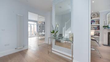 A modern interior with a glass console table, white walls, and a wooden floor.