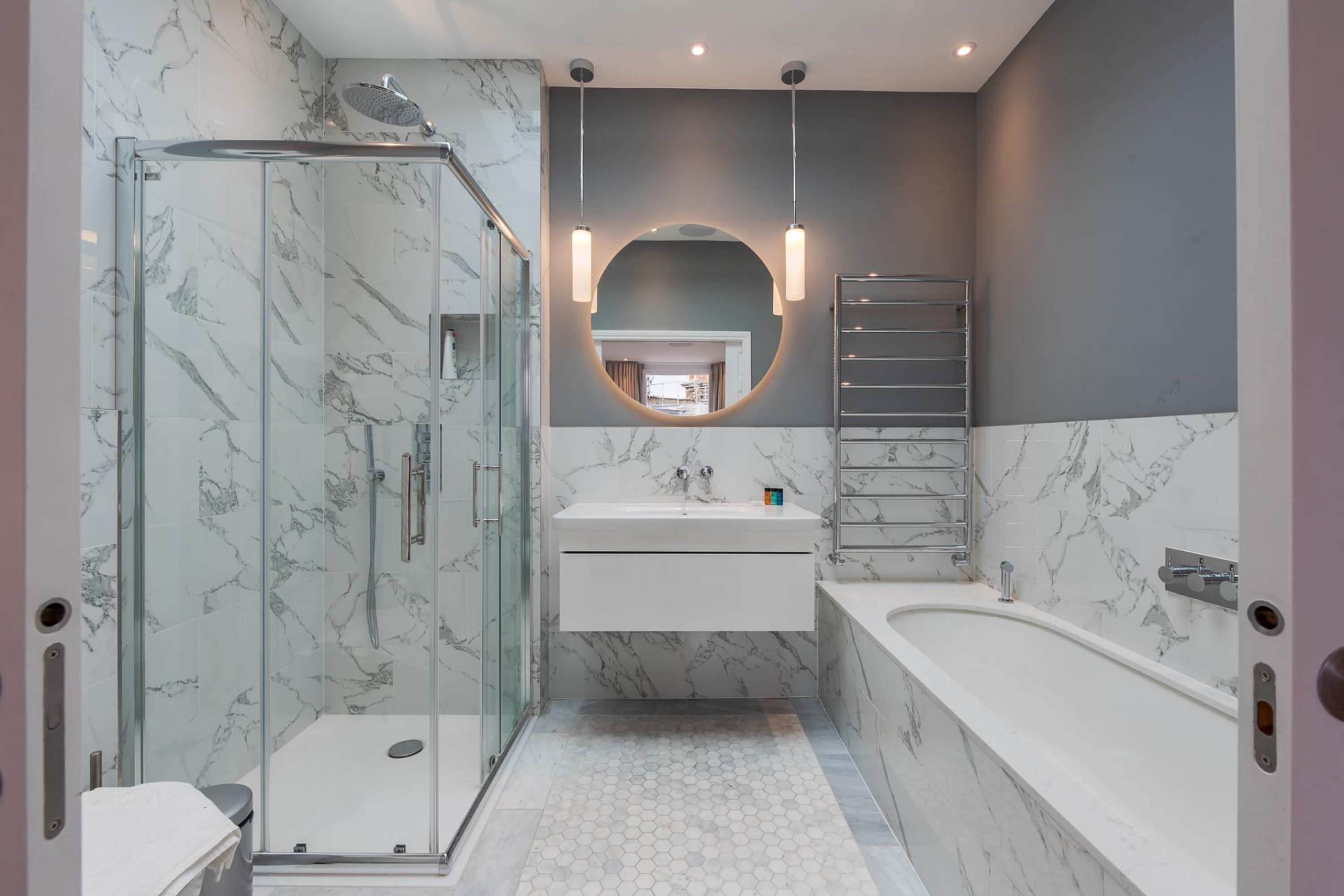 A modern bathroom with a glass-enclosed shower, a freestanding bathtub, and a vanity with a mirror.
