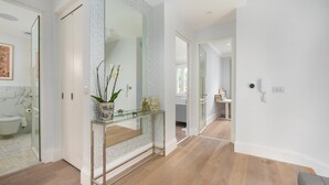 A modern bathroom with a glass shower enclosure, a marble-tiled sink, and a decorative vase with orchids. - Maida Vale Elegance (London)