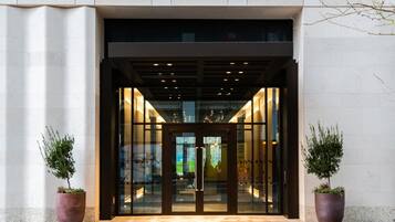 Welcome to our hotel, where guests can enter through a beautifully framed entrance with potted plants on either side.
