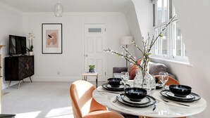 A dining area with a round table set for four, black plates, and clear glassware. - The Wellington Suite Next to Sloane Square (London)