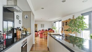 A modern kitchen with a central island, a dining area with a pink sofa, and a large window with a view.