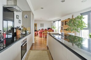 A modern kitchen with a central island, a dining area with a pink sofa, and a large window with a view.