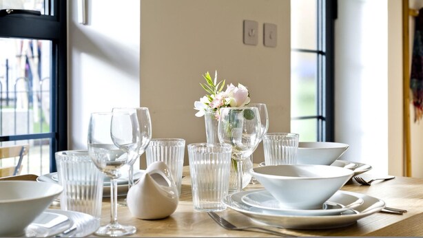 A dining table set with clear glassware, white plates, and a vase with flowers. - Greenwich Perfection (London)