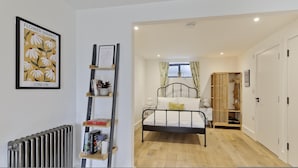 Ein Schlafzimmer mit einem Bett, einem Heizkörper, einem Bücherregal und einem gerahmten Bild an der Wand.