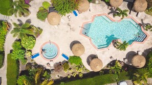 An aerial view of a resort with multiple swimming pools, lounge areas, and tropical landscaping. - Colibri Court (Jolly Harbour)