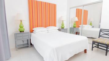 Una camera d'albergo ordinata con un letto grande, due comodini con lampade, una sedia e uno specchio.