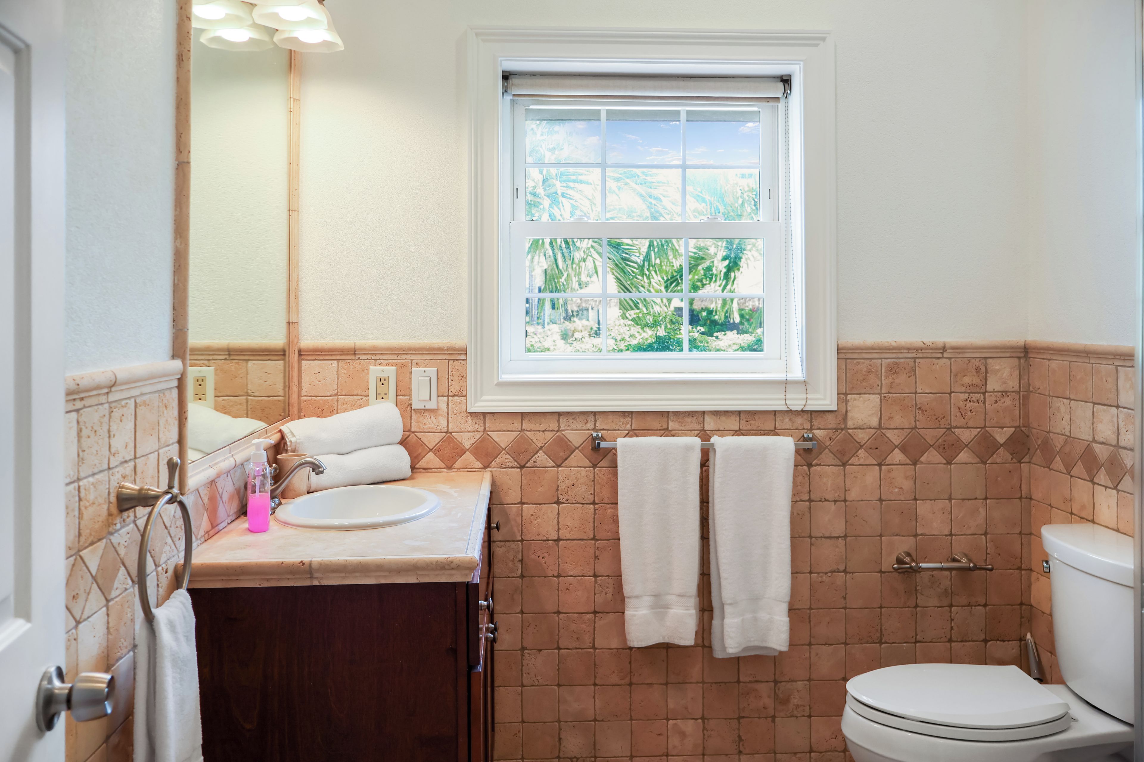 A bathroom with a window, a sink, a toilet, and a towel rack.