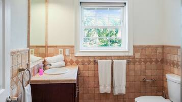 A bathroom with a window, a sink, a toilet, and a towel rack.