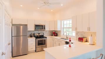 A modern kitchen with stainless steel appliances, white cabinetry, and a central island.