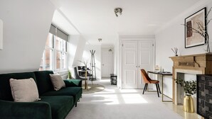 Una sala de estar moderna con un sofá verde, una chimenea y un comedor con mesa y sillas.