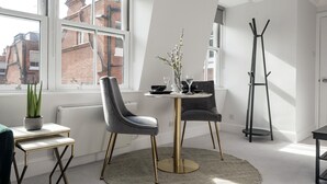 Un comedor moderno con una mesa redonda, dos sillas y un jarrón de flores.