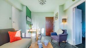 Ein gemütliches Wohnzimmer mit einer Couch, einem Sessel und einem Couchtisch mit Tassen.