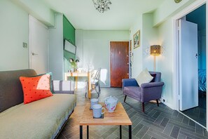 A cozy living room with a sofa, armchair, and a coffee table with mugs. - Hardwood Home (London)