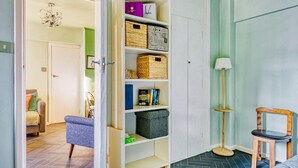 Ein Zimmer mit einem weißen Kleiderschrank, einem blauen Sessel, einer Stehlampe und einem Holzhocker.