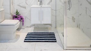 A bathroom with a toilet, sink, and shower area. - Stylish Modern 2-bedroom Apartment on Cromwell (London)