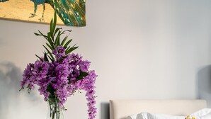 A bedroom with a mirrored dresser, a white sofa, and a purple flower vase. - Stylish Modern 2-bedroom Apartment on Cromwell (London)