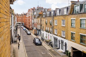 A narrow urban street lined with terraced houses, featuring a mix of brick and stone facades, some with visible balconies and windows. - At Home in Marylebone (London)