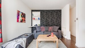 En moderne stue med en grå sofa, et træsofabord og tapet med et mønster.