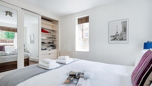 Et hotelværelse med en seng, et skab, et vindue og et billede i ramme på væggen.
