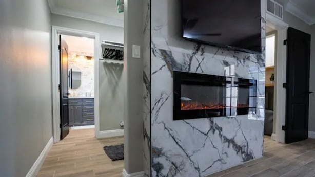 A modern kitchen with a built-in fireplace, marble backsplash, and wooden flooring.