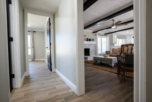 A spacious hallway with wooden flooring leading to a living area with a fireplace, a sofa, and a dining table.