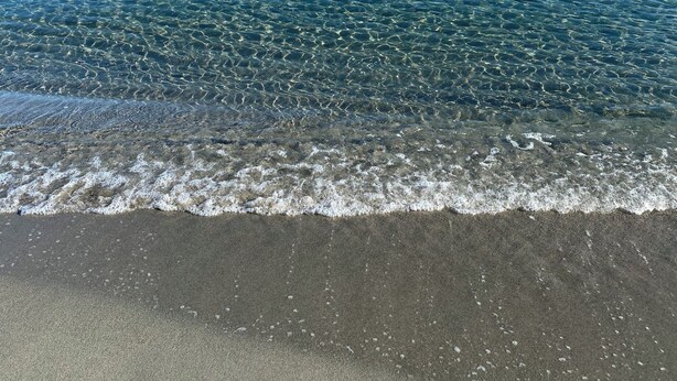Uma praia com águas claras e areal arenoso.