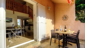 Uma sala de jantar com mesa posta para dois, uma escadaria e vista para a cozinha.