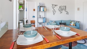Un coin repas avec une table en bois dressée pour quatre personnes, agrémentée de bols turquoise et d’assiettes blanches.