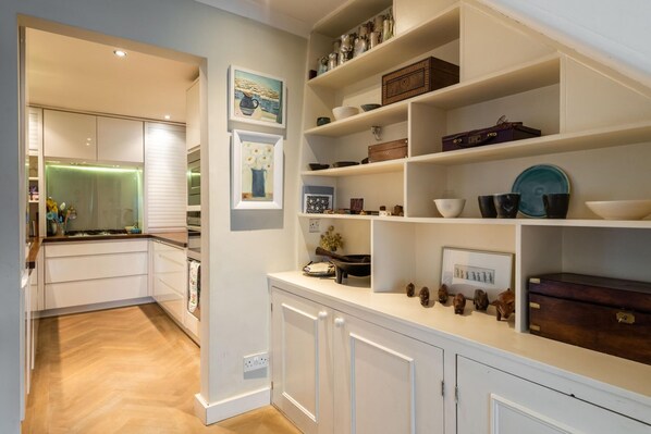 Kitchen area with modern design, featuring white cabinetry and a countertop, and ample storage for kitchenware.