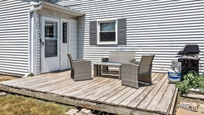 Une terrasse en bois avec des meubles en osier et un barbecue.