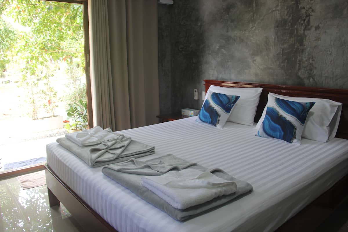Ein Hotelzimmer mit Bett, Handtüchern und Blick auf grüne Natur.