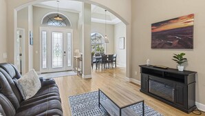 A spacious living room with a leather sofa, a fireplace, and a dining area with a table and chairs.