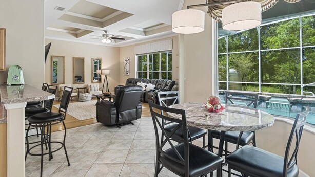 A spacious living area with a dining table, comfortable seating, and a view of a swimming pool.